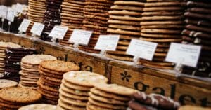 Assorted cookies elegantly stacked and labeled at a bustling market stall.