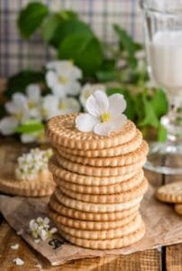A stack of fresh biscuits decorated with a flower next to a glass of milk, evoking a cozy breakfast mood.