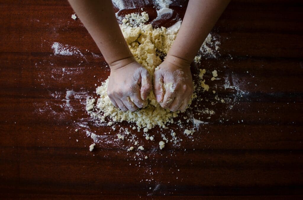 pexels-photo-9095 Close-up of hands kneading dough for baking on a wooden table, ideal for cooking themes.